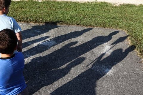 Shadows of students extend across an asphalt black top