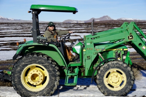 man smiling on large green tractor.