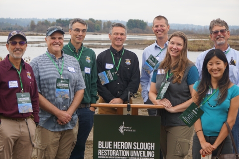 U.S. Fish & Wildlife Service staff behind a podium that says "Blue Heron Slough Restoration Unveiling"