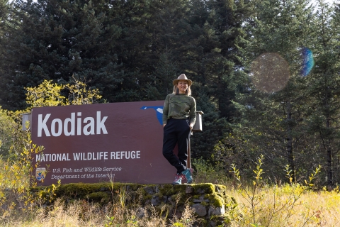 musician KT Tunstall standing in front of the Kodiak National wildlife Refuge sign