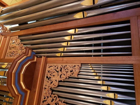 a closeup of an ornate set of vertical pipes on an organ pipe instrument