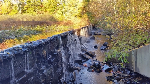 pond pours over a crumbling dam