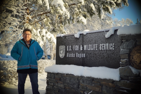 man in snow by a USFWS sign
