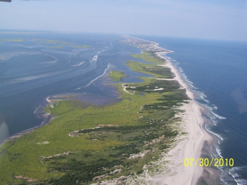 A barrier island with lush green growth on the far side 