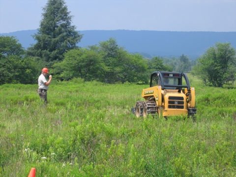 Heavy equipment used in a field with a volunteer guiding.