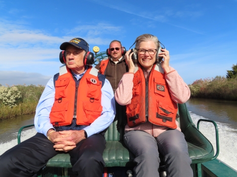man and woman in an air boat with life vests and headphones 