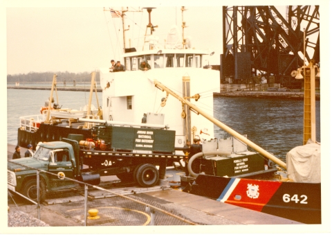 A hatchery truck is loading fish onto a large boat that is docked