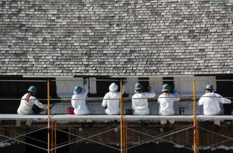In this photo: HistoriCorps volunteers work to repaint the siding to match the original color.