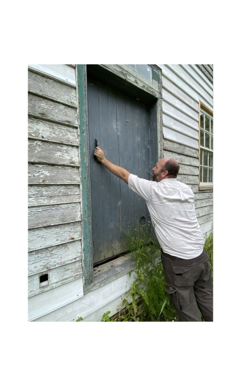 A man checks on a door on a white house on Jehossee Island.
