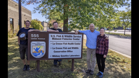 Four people stand in front of the Midwest Fisheries Center sign