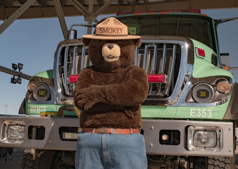 Smokey Bear standing in front of a fire truck