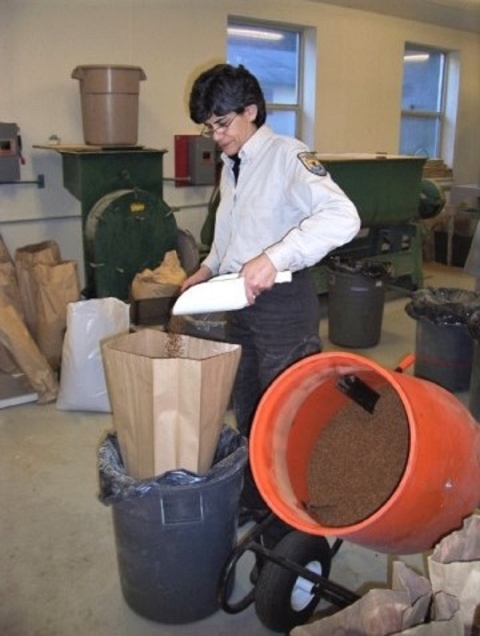 Woman using a scoop to fill a paper bag with fish feed pellets