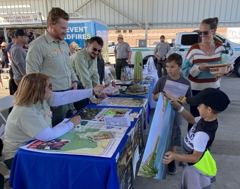 U.S. Forest Service personnel interact with children at an exhibit table