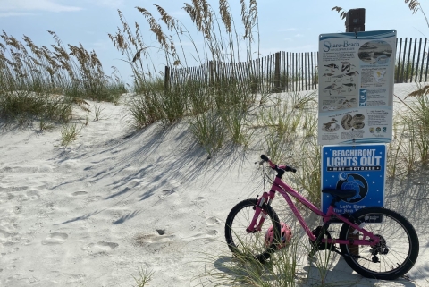 A bike against a sign on the beach.