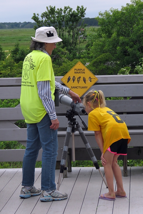 Image of volunteer helping child use a viewing scope