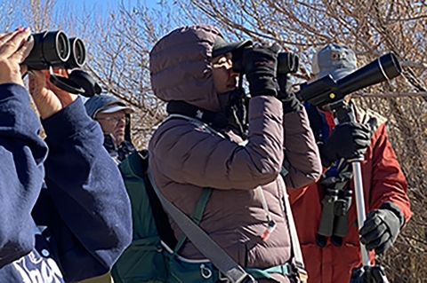 Woman in heavy jackey suing binoculars to find birds