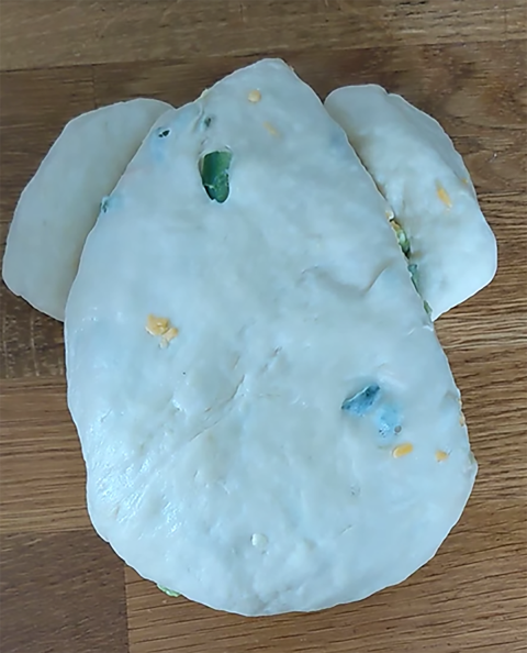 a ball of dough shaped into the body and hind legs of a frog