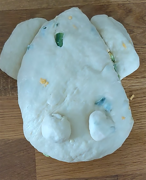 a ball of dough shaped into the body, hind legs, and eyes of a frog