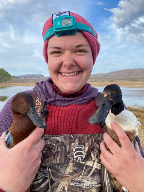Woman smiling while holding two ducks, one in each arm