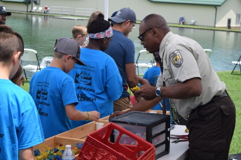 FWS employee hands out bait to kids near the pond
