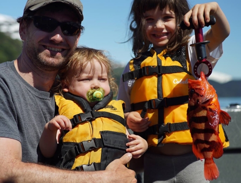 a family of 3 holding a striped orange fish