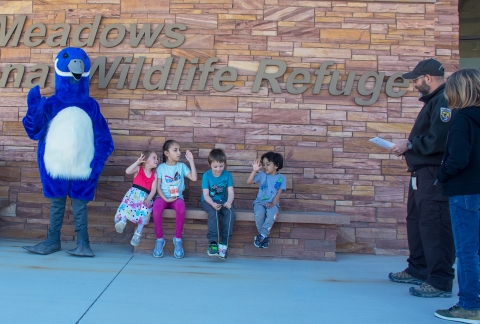 Children sititng on a bench with Puddles the blue goose