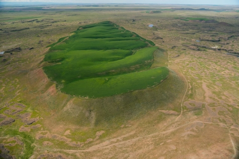 Crops of wheat growing on the top of a flood-carved mesa are a green contrast to the surrounding drier landscape.
