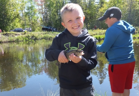 Young angler shows of a trout caught during FWS fishing event