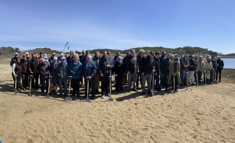 A group of people standing in a sandy area with shovels