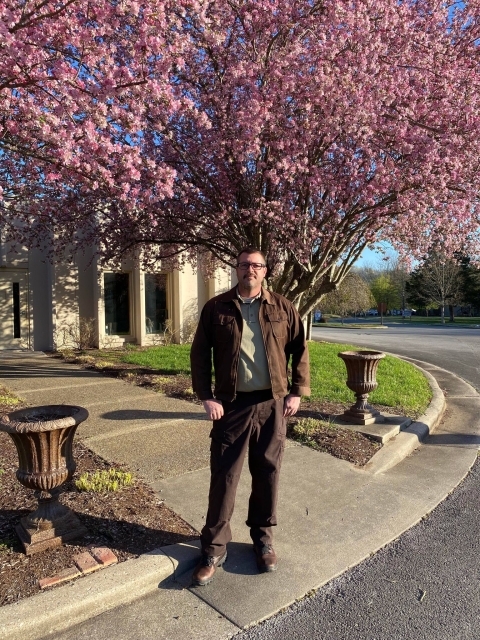 USFWS employee standing in front of blooming trees & building