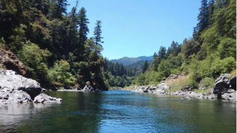 photo of river surrounded by rocks, trees, blue sky