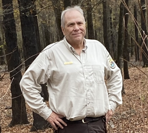 Michael Stroeh stands in the forest wearing a USFWS uniform. 