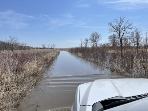 A vehicle stops on a flooded section of road