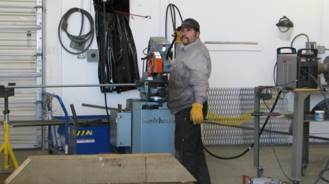 A man in a Service uniform performing metal fabrication at a maintenance shop