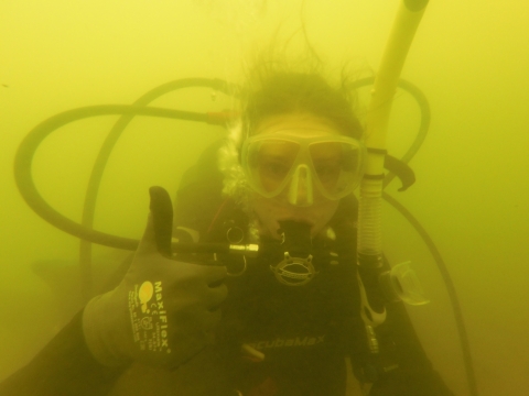 an murky underwater photo of a SCUBA diver holding a thumbs up