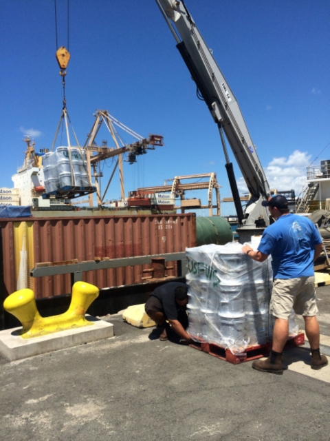 Pallets of buckets are loaded on to a ship. 