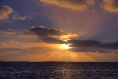 A sun rising through the clouds at Midway Atoll. 