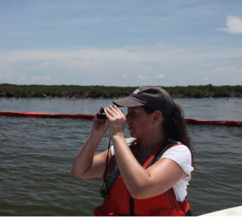 Vanessa Kauffman holds binoculars up to her eyes as she searches for injured wildlife by boat. 
