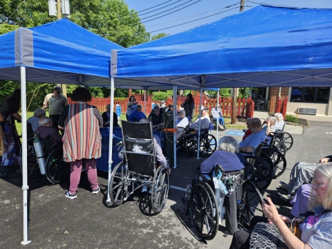 Group of elderly/disabled people gathered around fish tank under tents
