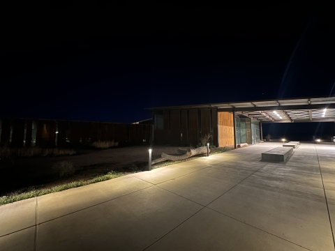 a walkway to a visitor center is illuminated with path lights facing the ground, not the air