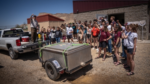 A large group of people celebrating near a truck full of razorback sucker