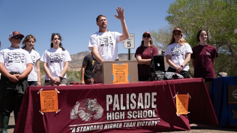 A group of people stand behind a table labeled Palisade High School