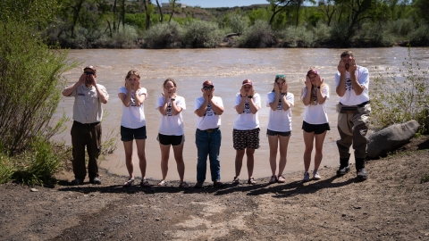 A group of people making fish faces while standing in front of a river