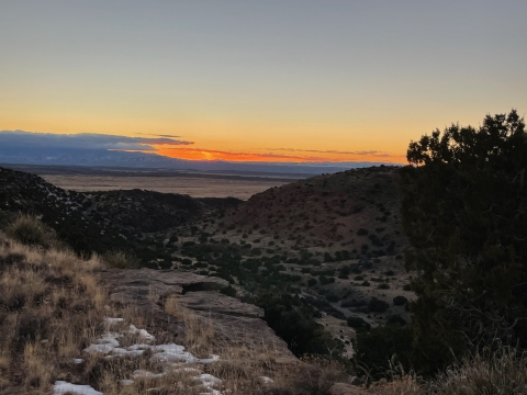 a view of sunset from the top of a ridge across an arid landscape