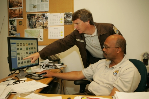 Photo of service employees discussing management needs while looking at data on a computer