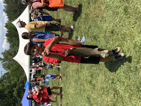 Boy holding large rainbow trout with hand scale