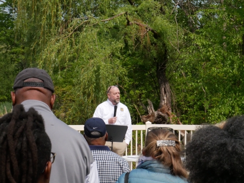 Acting deputy regional director Scott Kahan speaks into a microphone onstage in front of a crowd of community partners and residents about the Urban Bird Treaty