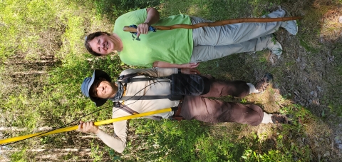 Scott and Shannon in the woods holding field equipment