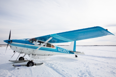 a turquoise and white ski plane sits on the snow