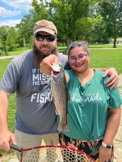 A couple posing with a Rainbow trout